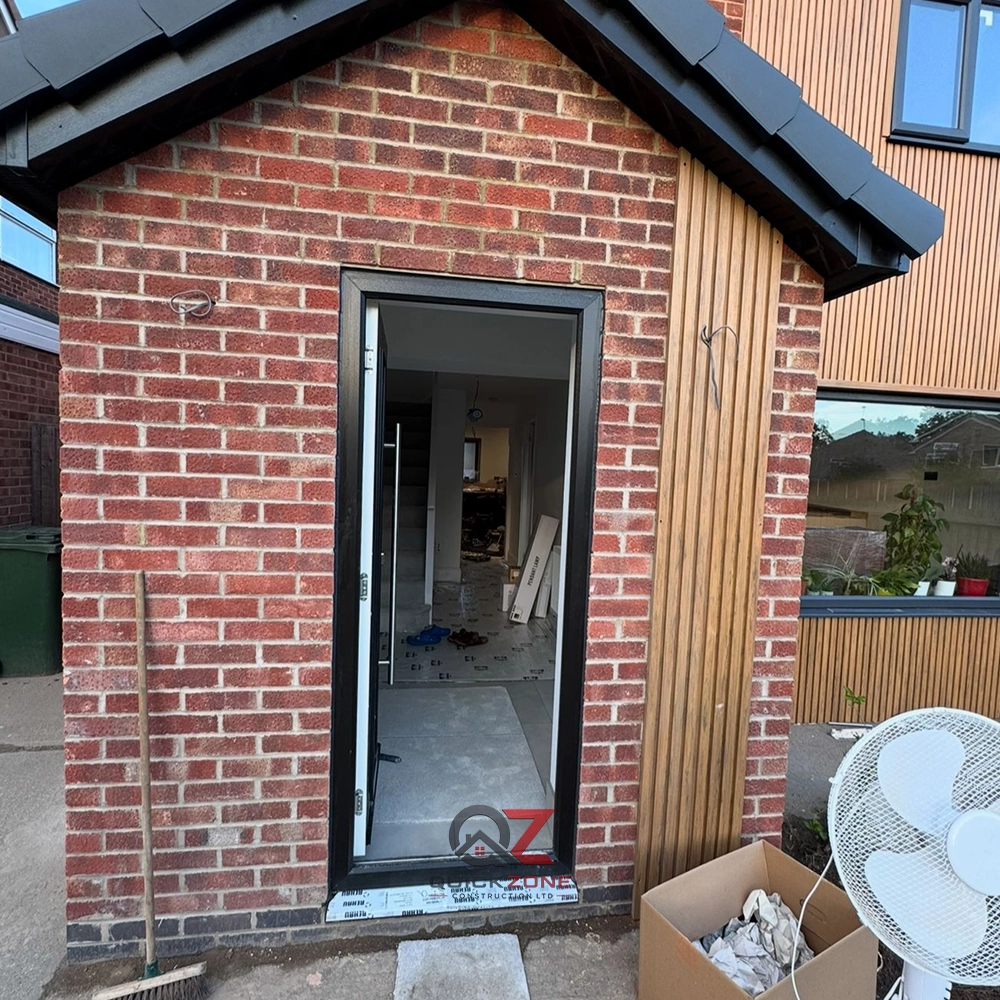 brick and stone home extension with scaffolding and workers