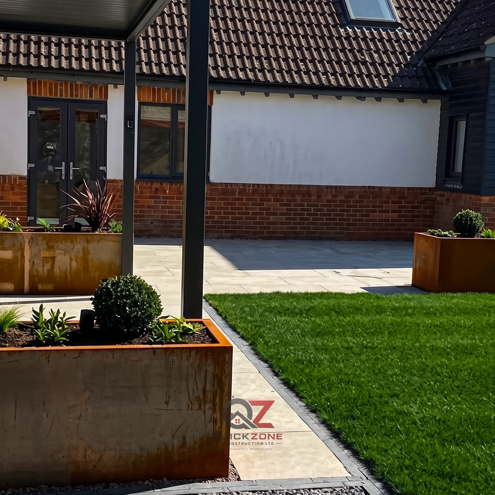 modern house side view with paved area, large planters and lawn
